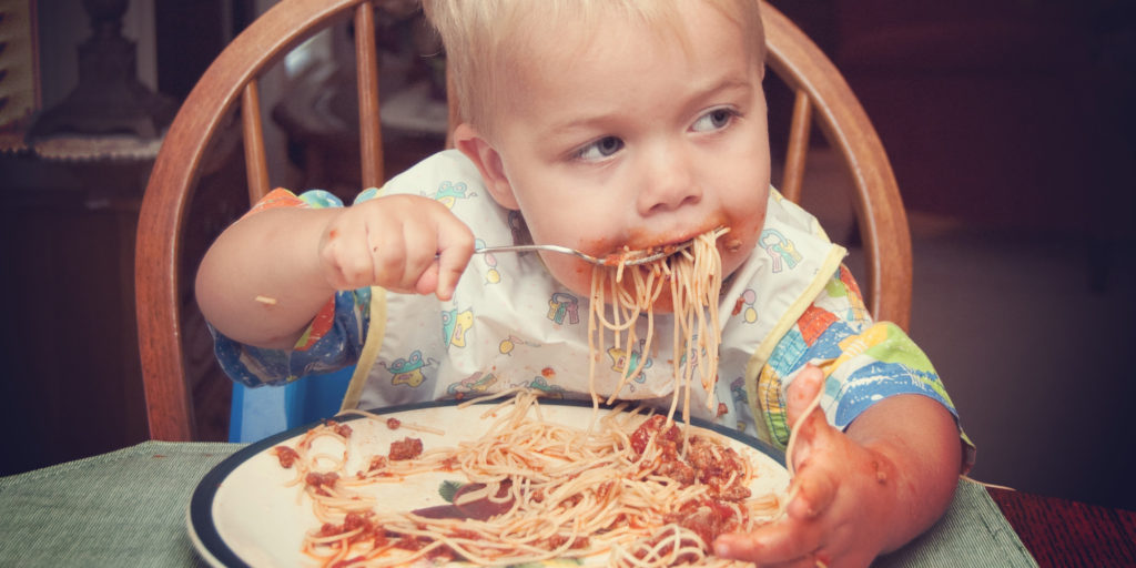 Danish boy feeding himself spaghetti